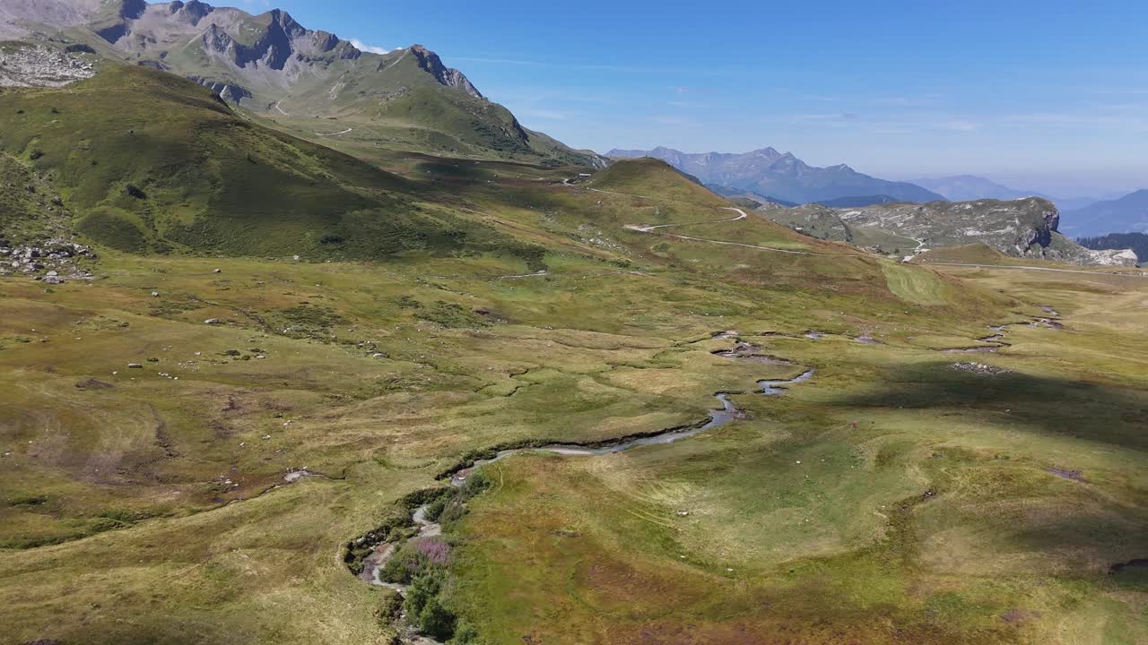Drone che vola lateralmente sopra una valle montana con un piccolo fiume in 4K