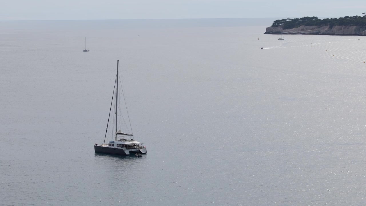 Veduta ampia di un catamarano a vela di lusso che galleggia sulle calme acque del Mediterraneo a Cassis, Francia