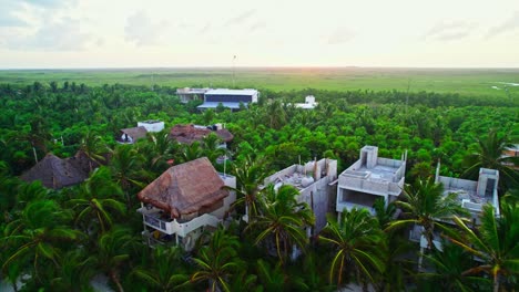 Imágenes-Aéreas-De-Exuberantes-Hoteles-Y-Edificios-De-La-Selva-Tropical-Con-Una-Puesta-De-Sol-De-Ensueño-En-El-Fondo