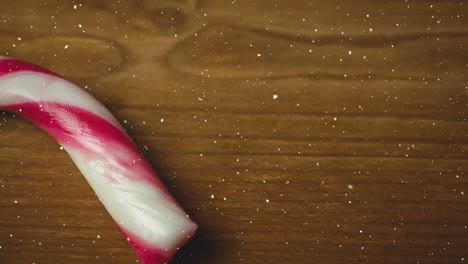 snow falling over close up of candy can on wooden surface