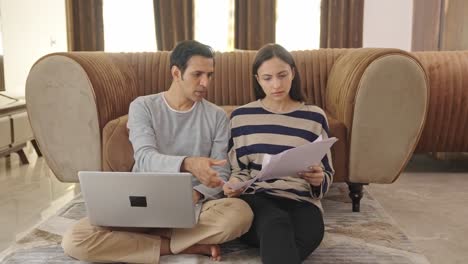 sad indian couple discussing and working on laptop