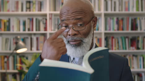 Retrato-De-Un-Hombre-De-Negocios-Afroamericano-Maduro-Con-Barba-Y-Gafas-Investigando-Un-Libro-De-Lectura-En-Un-Estudio-De-Biblioteca