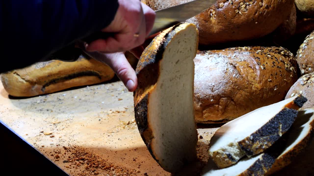 Il venditore di pane taglia grandi fette di pane al mercato