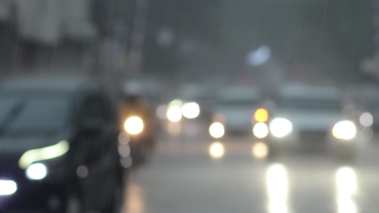 Blurry footage of highway with vehicle headlights during heavy rain condition