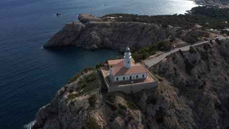 drone shot of light house far de capdepera in mallorca revealing big shore lines and the island in the background