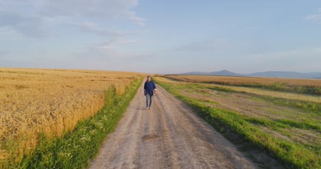 male farm researcher standing on dirt road amidst fields 3