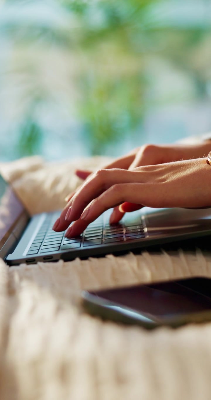 Primo piano di una donna che digita sulla tastiera del laptop a casa