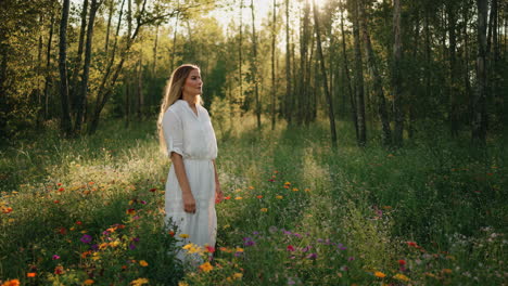 woman in white dress standing in a sunlit field of wildflowers
