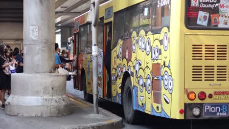 bus with cartoon characters stops, passengers board and alight.