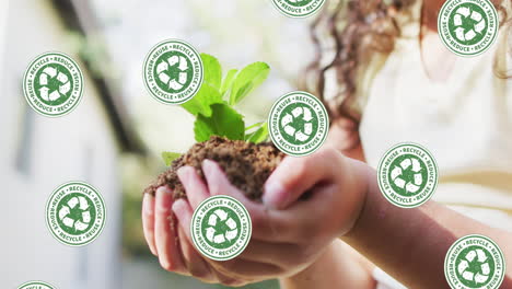 animation of recycling green signs over caucasian girl holding seedling