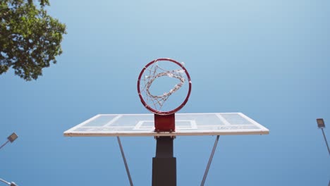 vista de abajo de la pelota de baloncesto negra cayendo en bucle en la cancha de streetball al aire libre, cámara lenta, jugador anotando un gol