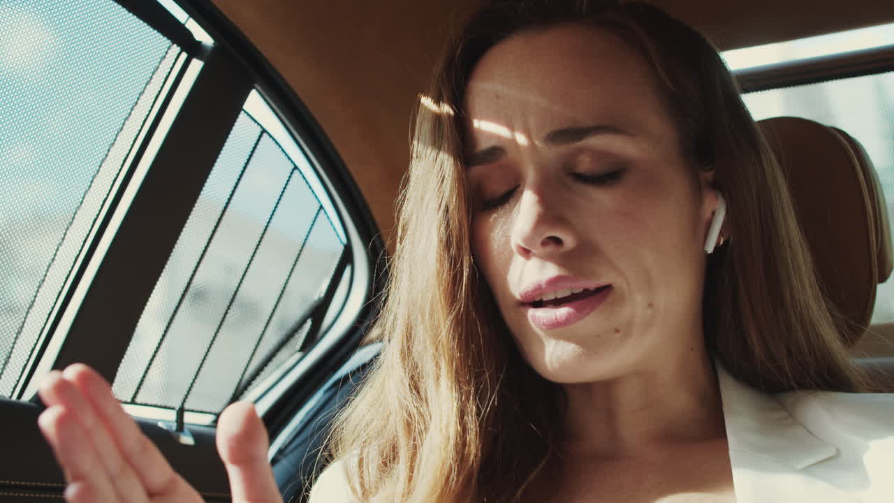 retrato de una mujer de negocios ansiosa discutiendo por teléfono en un auricular en un coche de negocios.