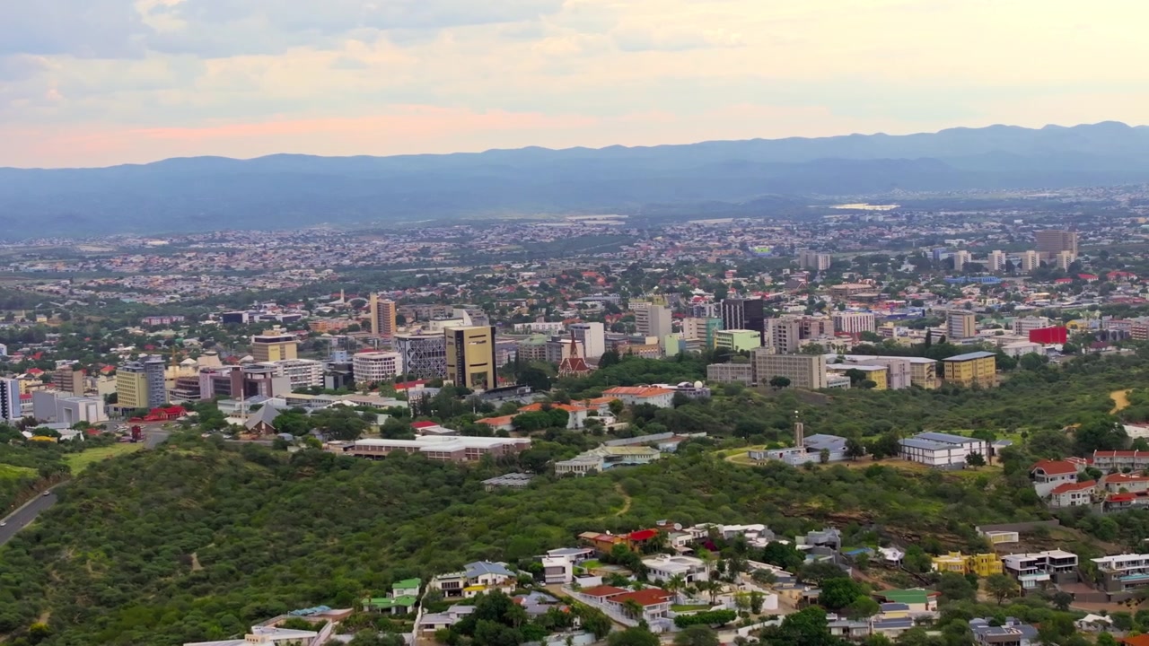 Veduta aerea del quartiere centrale degli affari di Windhoek con moderni grattacieli tra verdi colline. Una capitale estesa circondata da montagne.
