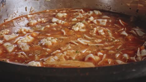 stock cube being placed in middle of simmering vegetable soup