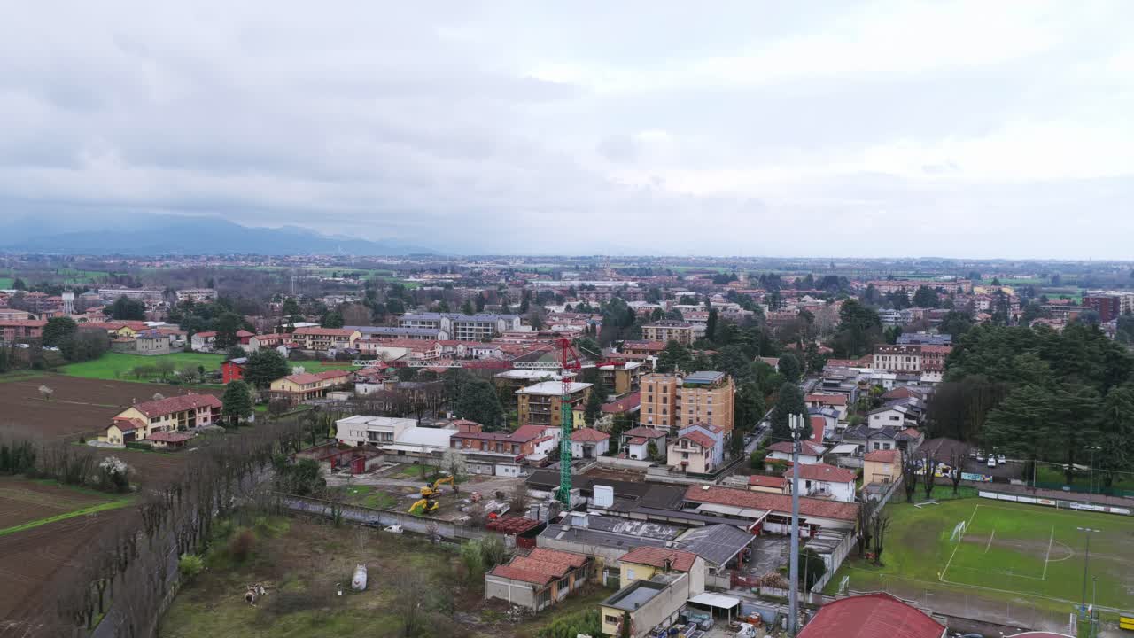 Vimercate, edifici residenziali e campi circostanti in una giornata nuvolosa, Lombardia, Italia. Vista aerea da dietro