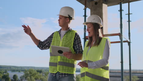 business building teamwork technology and people concept - smiling builders in hardhats with tablet pc computer outdoors