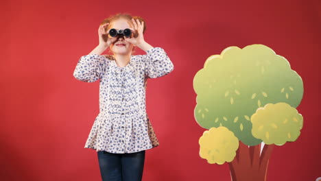 little girl looking through binoculars. happy childhood. studio shooting of children