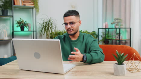 man sitting on home couch looking at camera making video conference call with friends or family
