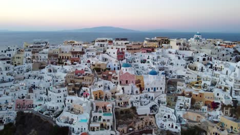 drone shot of oia famous cliffside white houses in santorini, greece