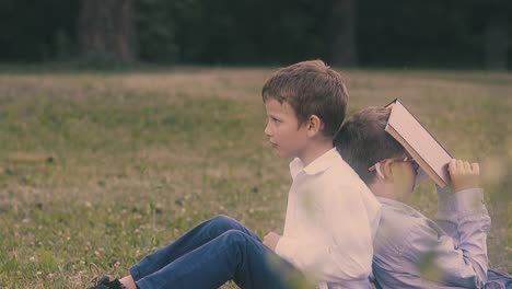 boy in white shirt throws away book leaning on sleeping boy