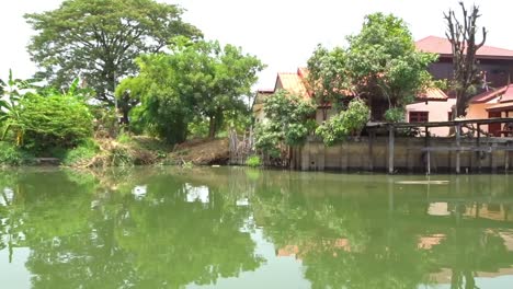 View-looking-out-from-the-side-of-a-boat-moving-slowly-along-on-a-canal-in-Thailand