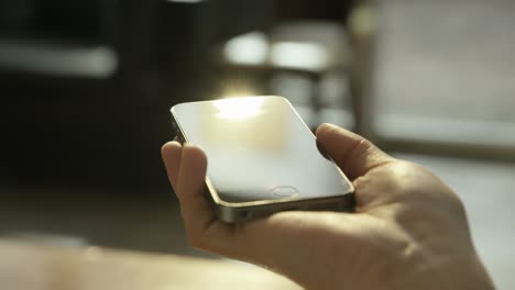 female hands with smart phone device on a sunny interior.