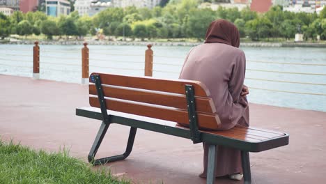 mujer sentada en un banco junto al lago