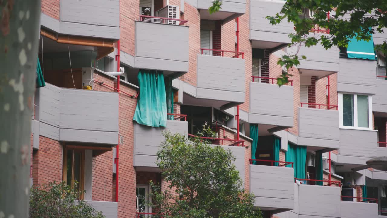 balcones en forma de triángulo en una fila con cortinas verdes y paredes de ladrillo rosa