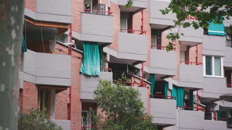 triangle formed balconies in a row with green curtains and pink brick stone walls