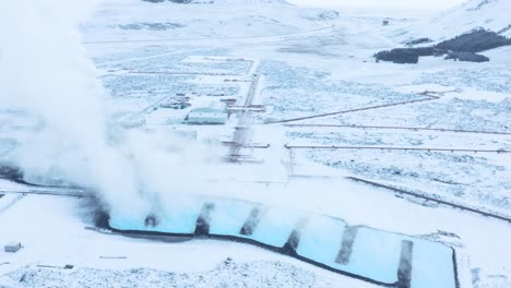 steam rises from spin off blue water of svartsengi geothermal power plant