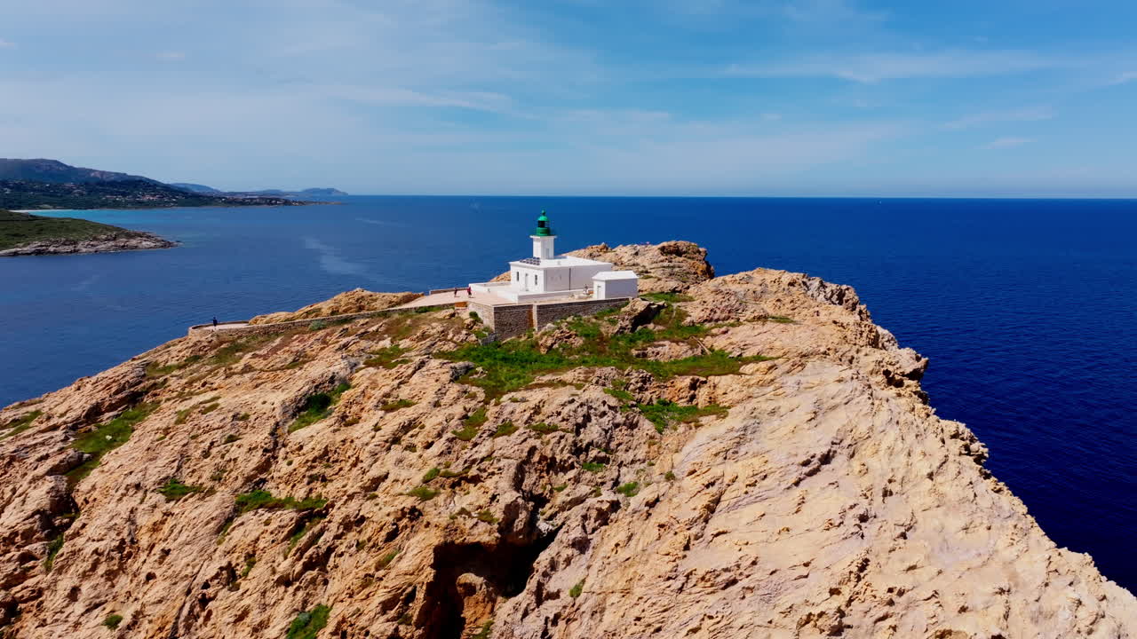 Aerial drone shot over Ile de la Pietra at the coastal town of Ile-Rousse in the Balagne region in Corsica, France. View of the White lighthouse on top of the cliff overlooking the landscape