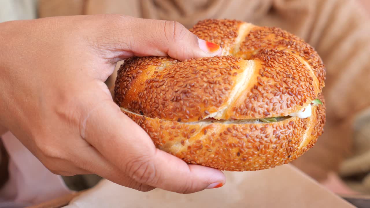 Person eating a Turkish Simit Sandwich