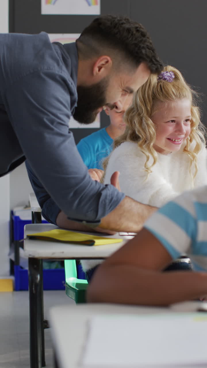 Vertical video of happy male teacher and diverse schoolchildren in school classroom