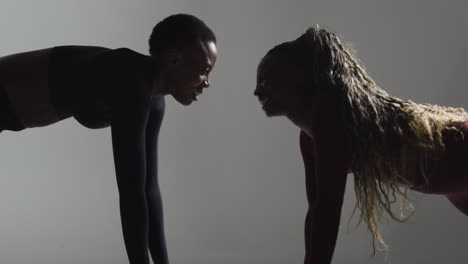 studio shot of two women wearing gym fitness clothing facing each other exercising 3