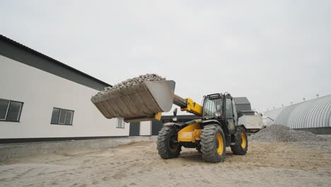 tractor moves rubble to truck. excavator-loader rakes rubble from pile at construction site and loads dump truck. clearing site