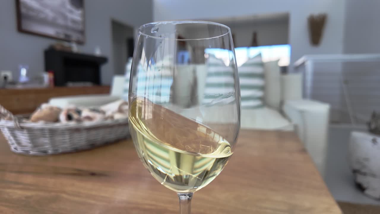 girando un vino blanco dorado en una copa en una acogedora casa mediterránea