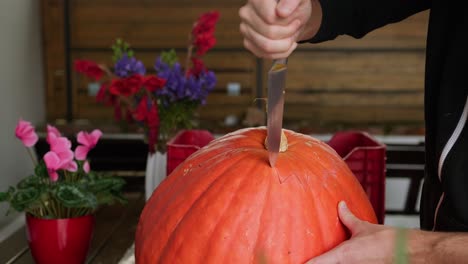 Gran-Calabaza-Tallada-Para-Decoración-Espeluznante-De-Halloween,-Cortando-La-Parte-Superior-Con-Un-Cuchillo,-Plano-Amplio