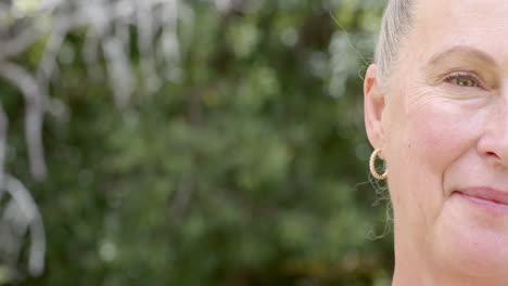 senior woman in garden wearing hoop earring, looking thoughtfully into distance, copy space