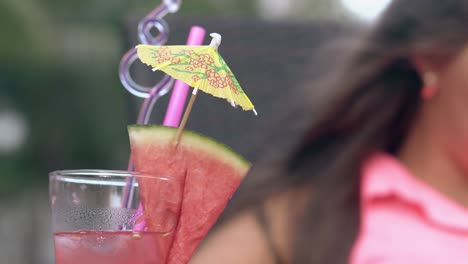 tall glass with watermelon stands in front of young woman