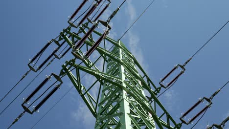 Líneas-Eléctricas-De-Alto-Voltaje-Y-Pilón,-Tiro-De-ángulo-Bajo-Con-Cielo-Azul-En-El-Fondo---Deslizándose-A-La-Derecha