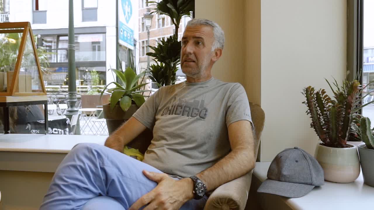 Anziano che fa smorfie espressive mentre parla con amici in una caffetteria.