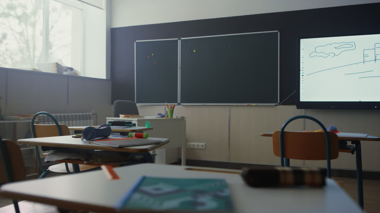 School classroom with chalkboard. School desks and chairs with supplies