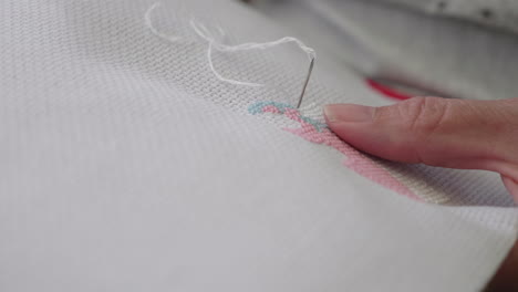 a close up of a lady sewing cross stitch, only the hands are visible