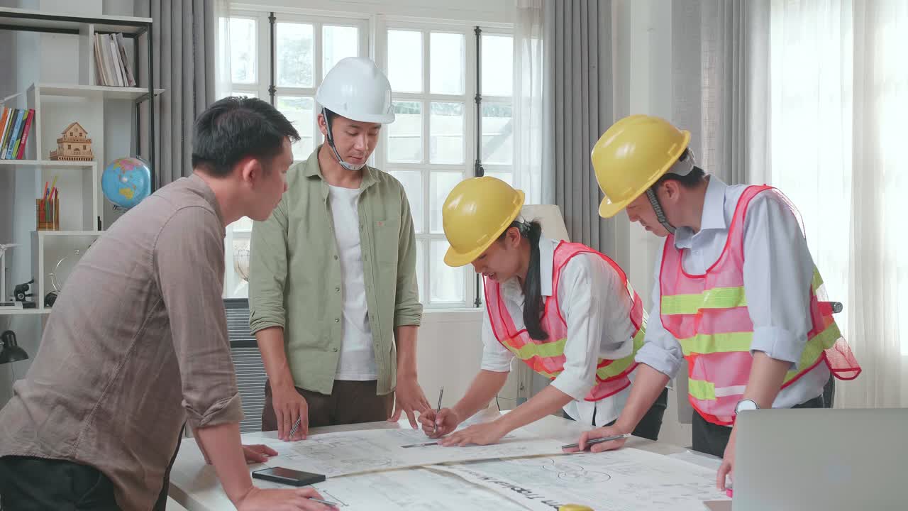 Three Asian Engineers With Helmets Helping A Man Drawing Building Construction At The Office