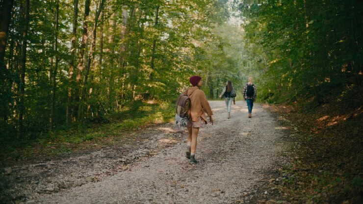 Young Woman Walking On Footpath With Friends In Forest