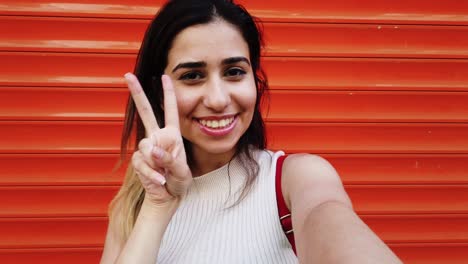 hermosa joven se toma selfie con un teléfono inteligente frente a un fondo naranja y rojo