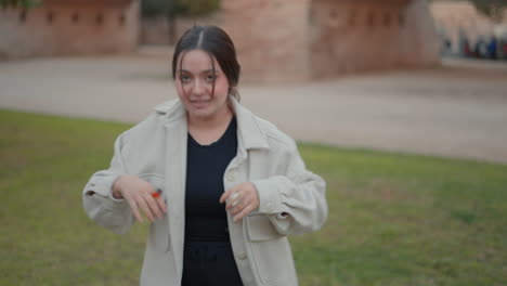 woman putting on jacket in park