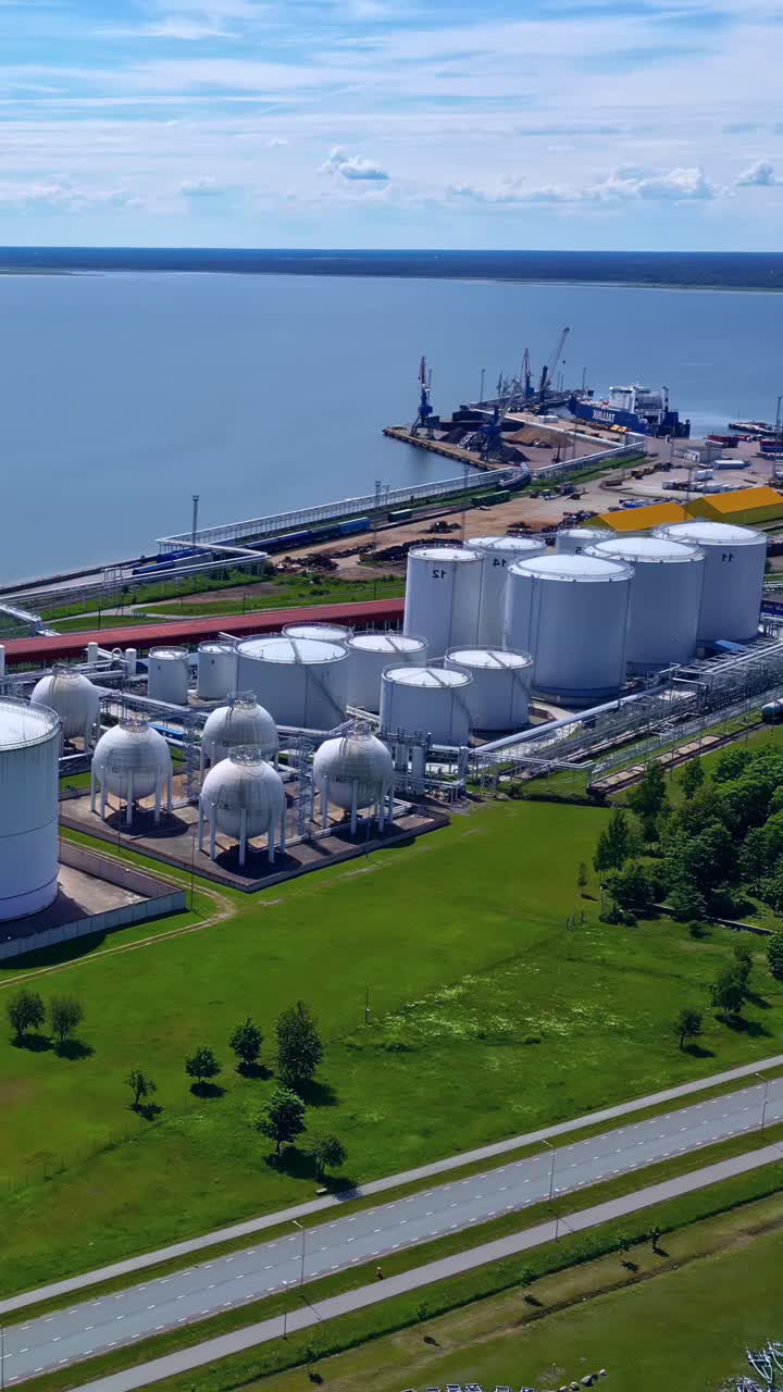 Vertical View Of Multiple Storage Tanks And Port Facilities With Cranes And Ship. Aerial Shot