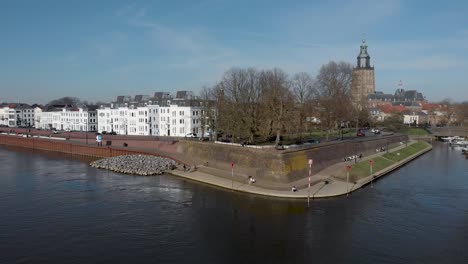 Aerial-view-and-reveal-of-embankment-of-medieval-Hanseatic-city-Zutphen,-The-Netherlands,-with-entrance-to-small-Vispoorthaven-or-Gelre-port-connected-to-the-river-IJssel