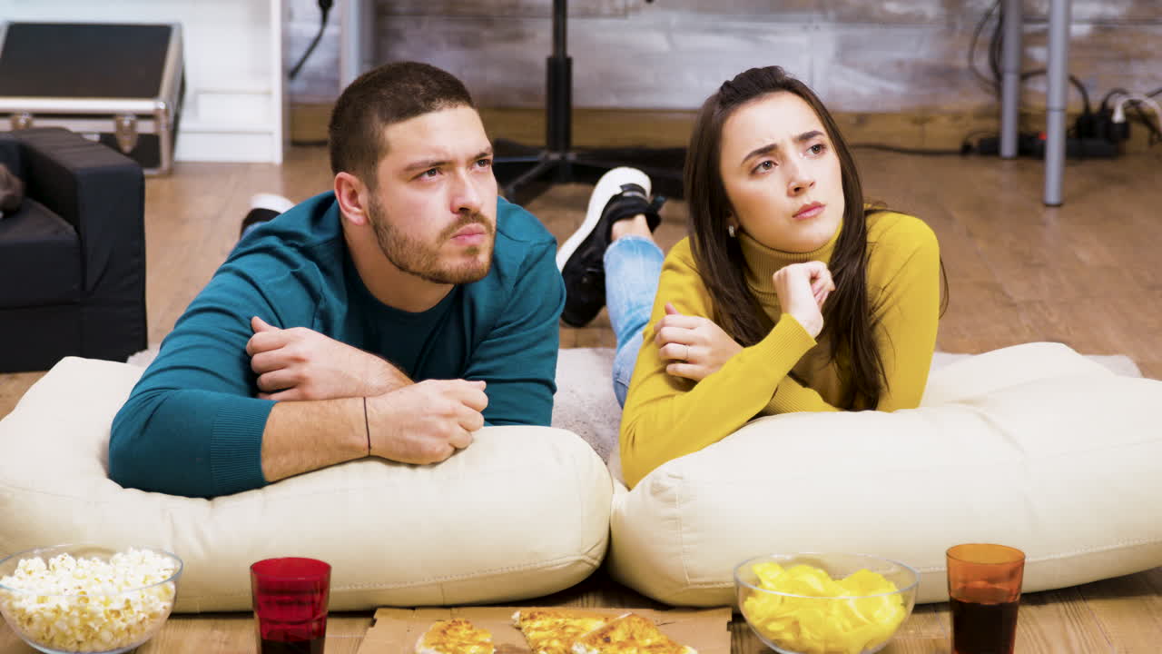 Casal assistindo TV com lanches